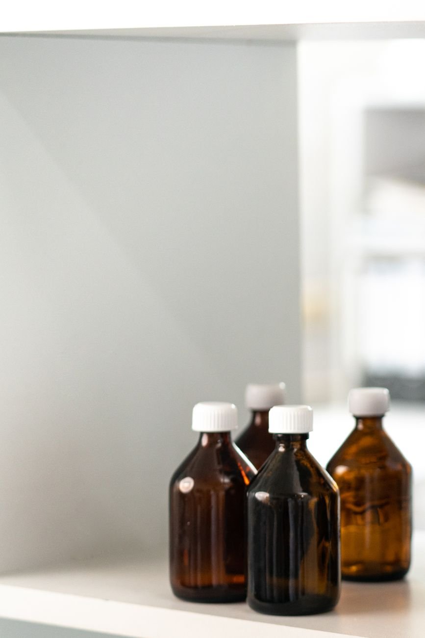 Four brown glass bottles with white caps on a shelf.